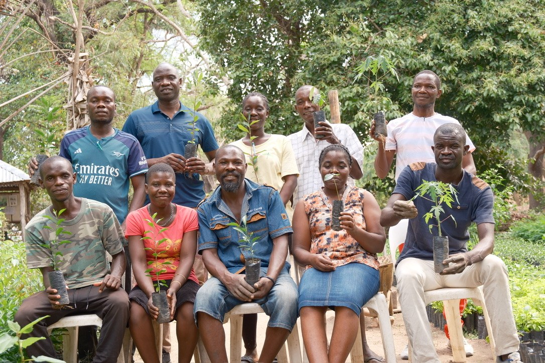 Root to Fruit participants holding young tree seedlings together outdoors.