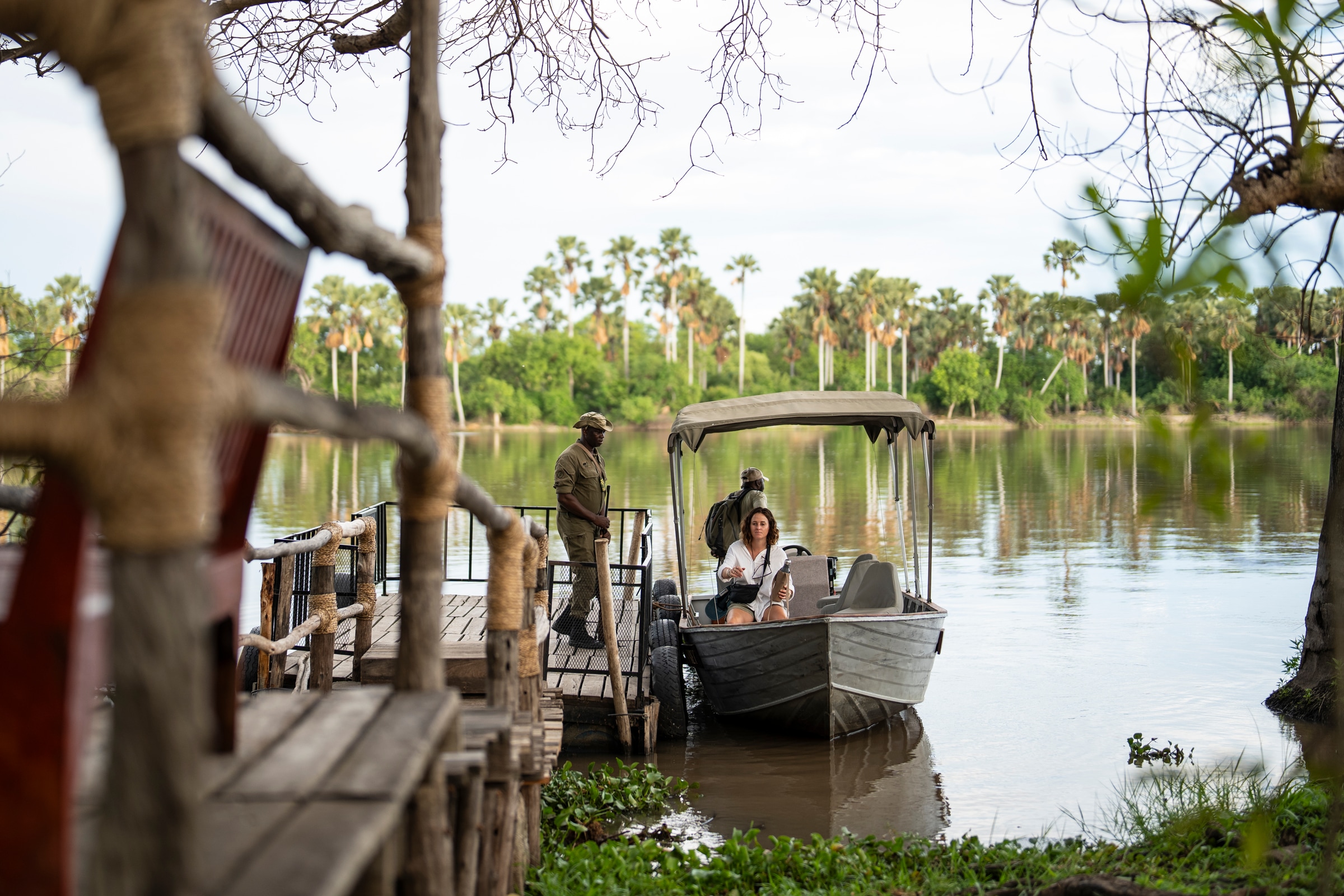 Guests aboard a safari boat alongside a wooden jetty.