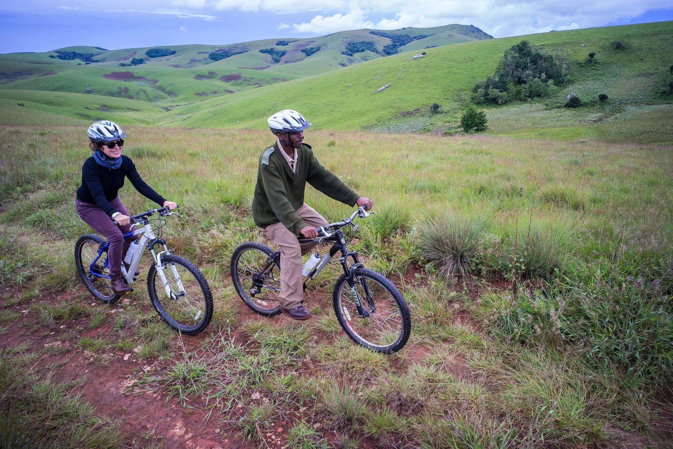 A guide and guest mountain biking through Nyika grassland.