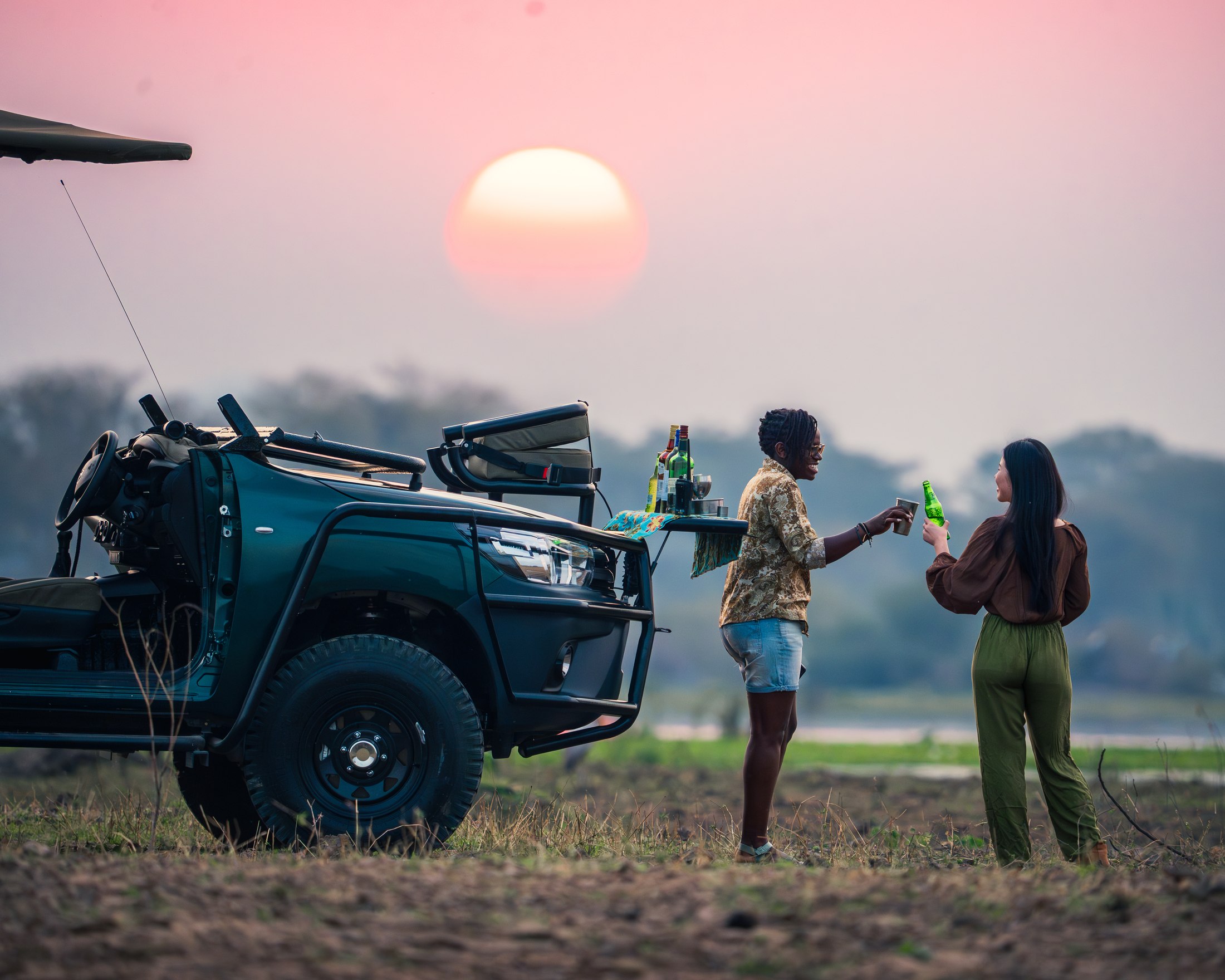 Guests enjoying sundowners beside a Mvuu safari vehicle.