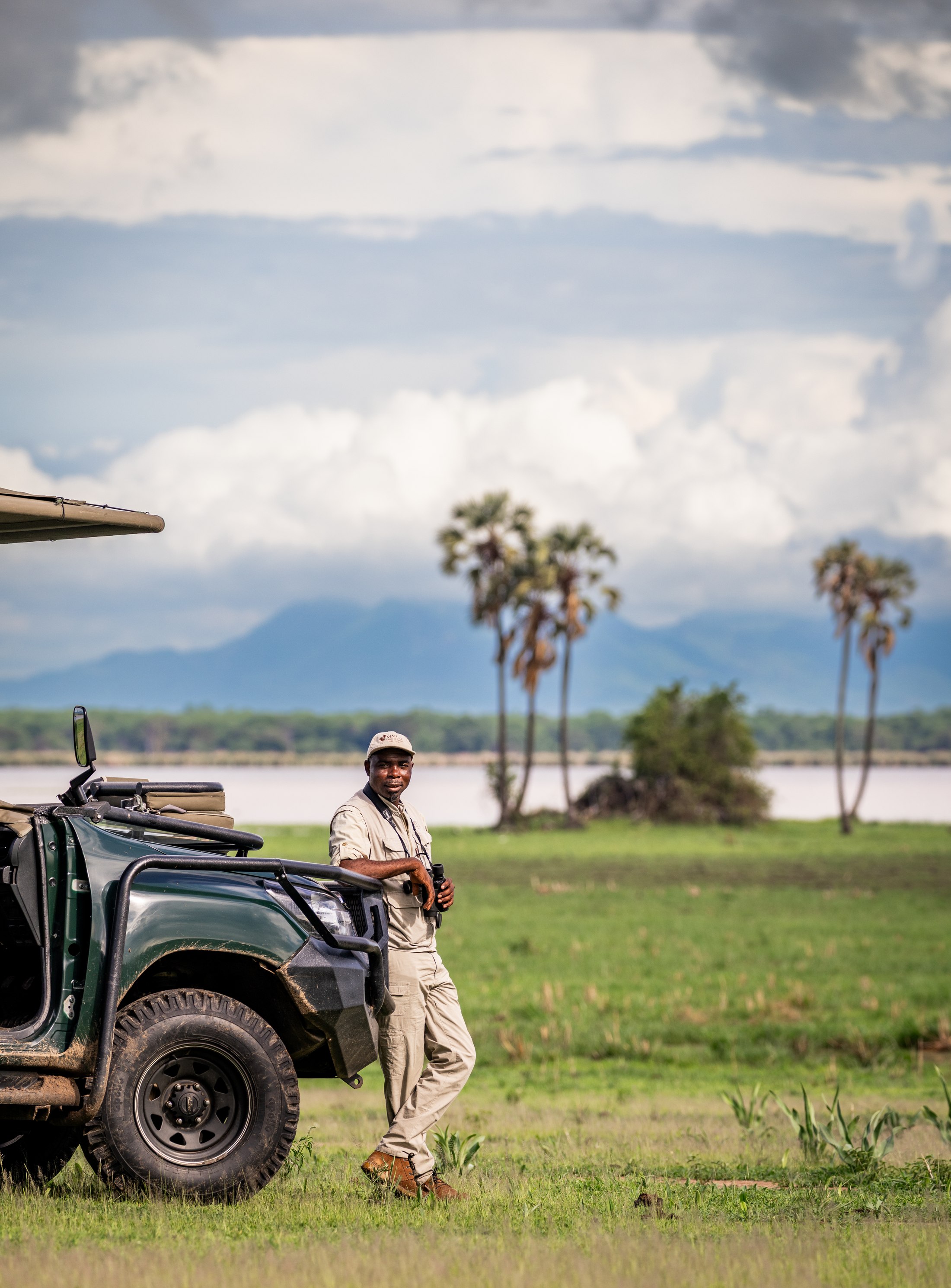 David, a Mvuu guide, beside a safari vehicle.